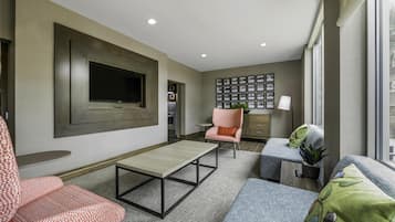 A modern living room with a flat-screen TV, a coffee table, and seating areas.