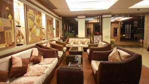 Eine geräumige Lobby mit Korbmöbeln, einem zentralen Sofa und großen, abstrakten Gemälden an den Wänden.