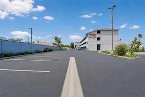 Um estacionamento que dá acesso a um motel, com céu claro.
