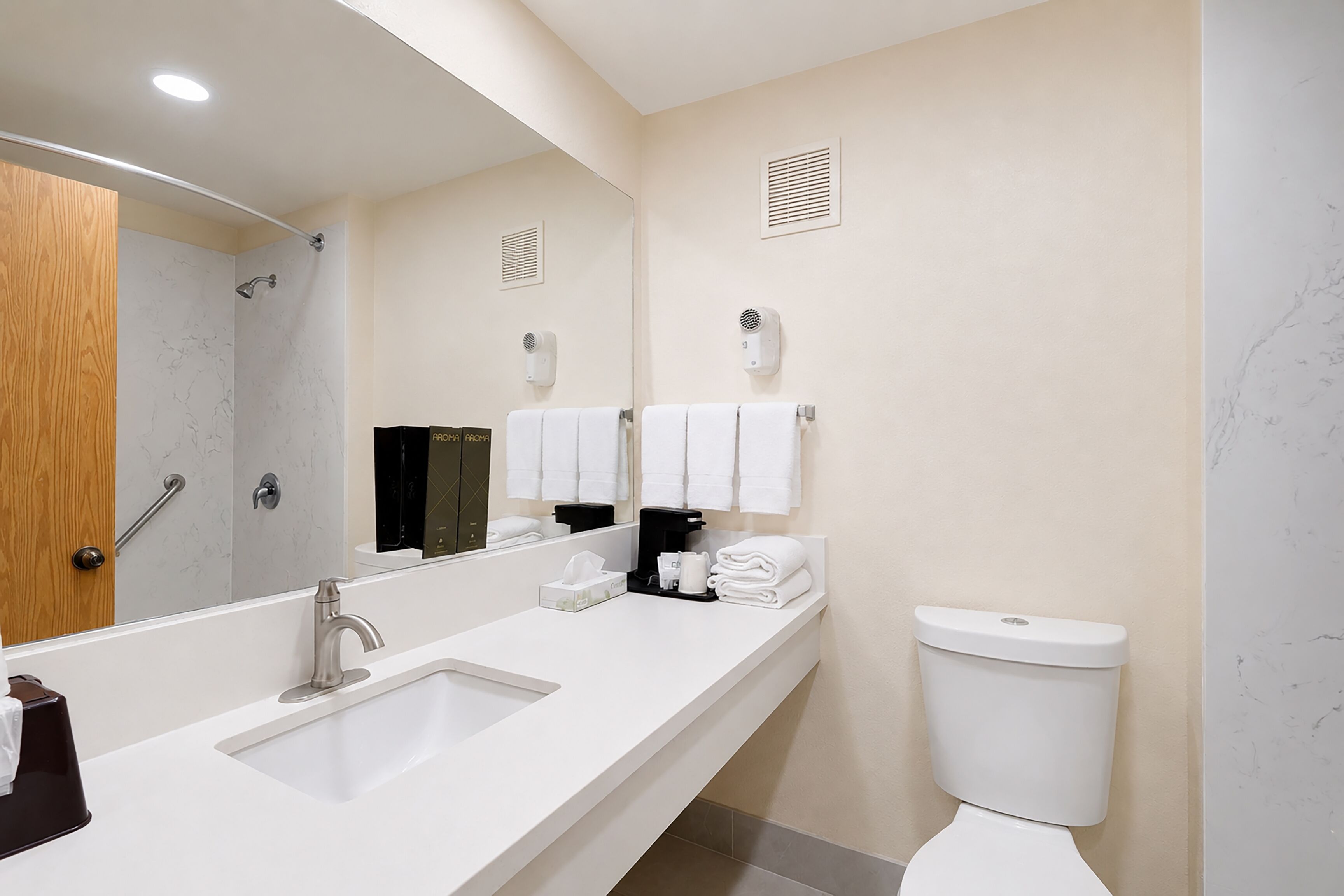A modern bathroom with a large mirror, a sink, a toilet, and a shower area.