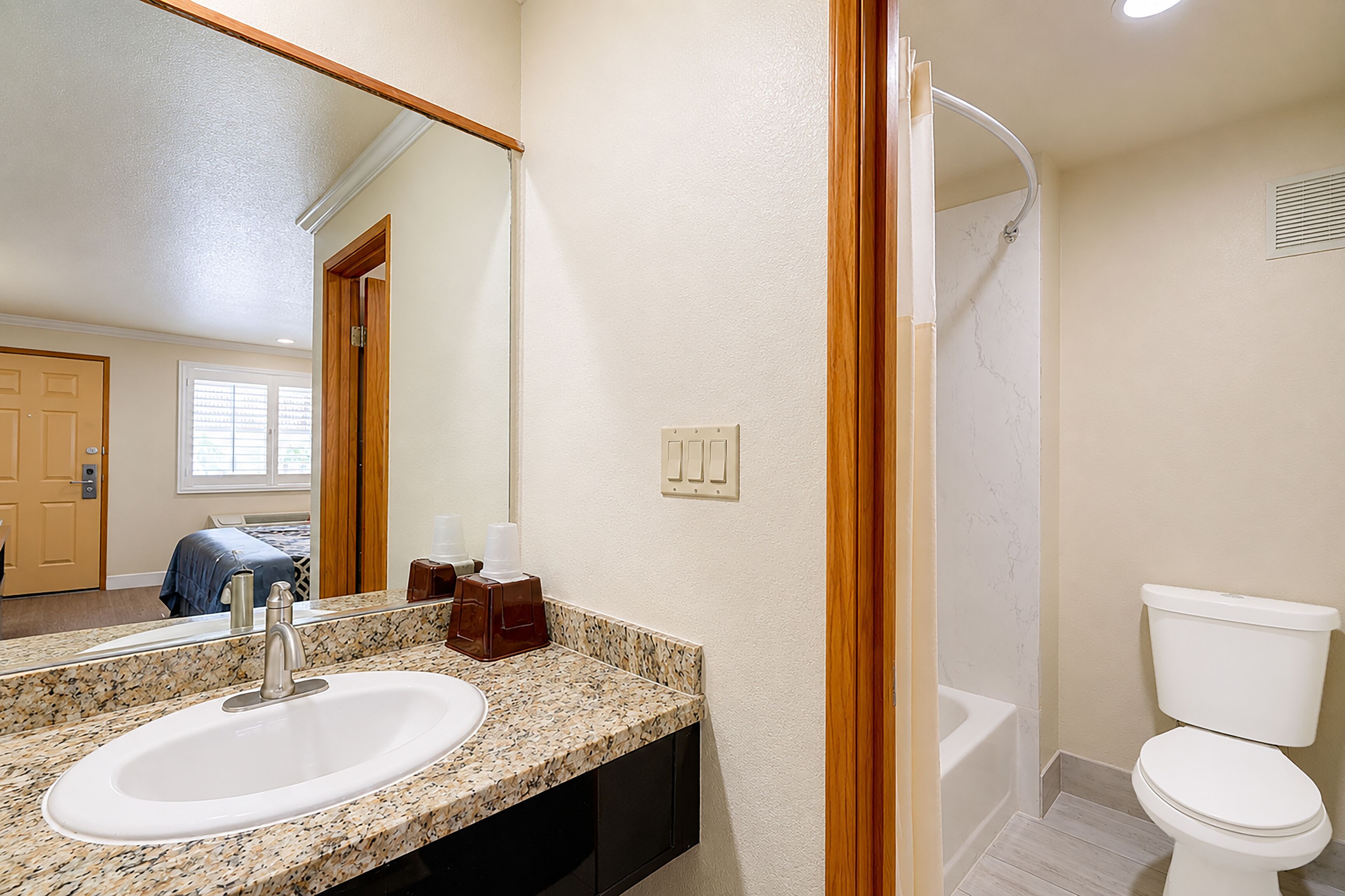 A bathroom with a sink, mirror, toilet, and shower.