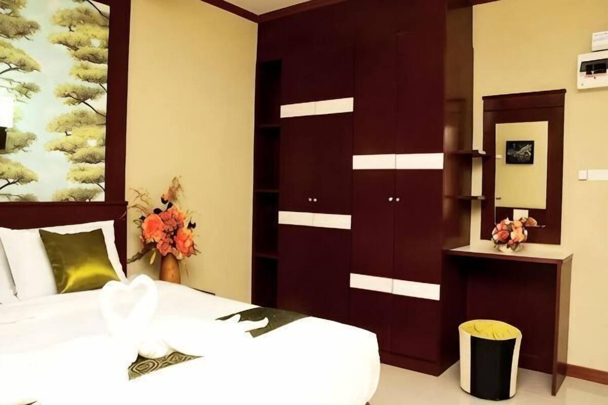 Habitació d'hotel amb un llit, un armari, una tocador amb mirall i un petit cubell de brossa.