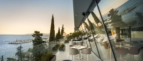 Una terraza moderna al aire libre con mobiliario y vista al mar.