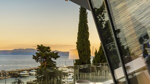 Un espacio de descanso moderno al aire libre con mesas y sillas, con vistas a un cuerpo de agua y montañas distantes.