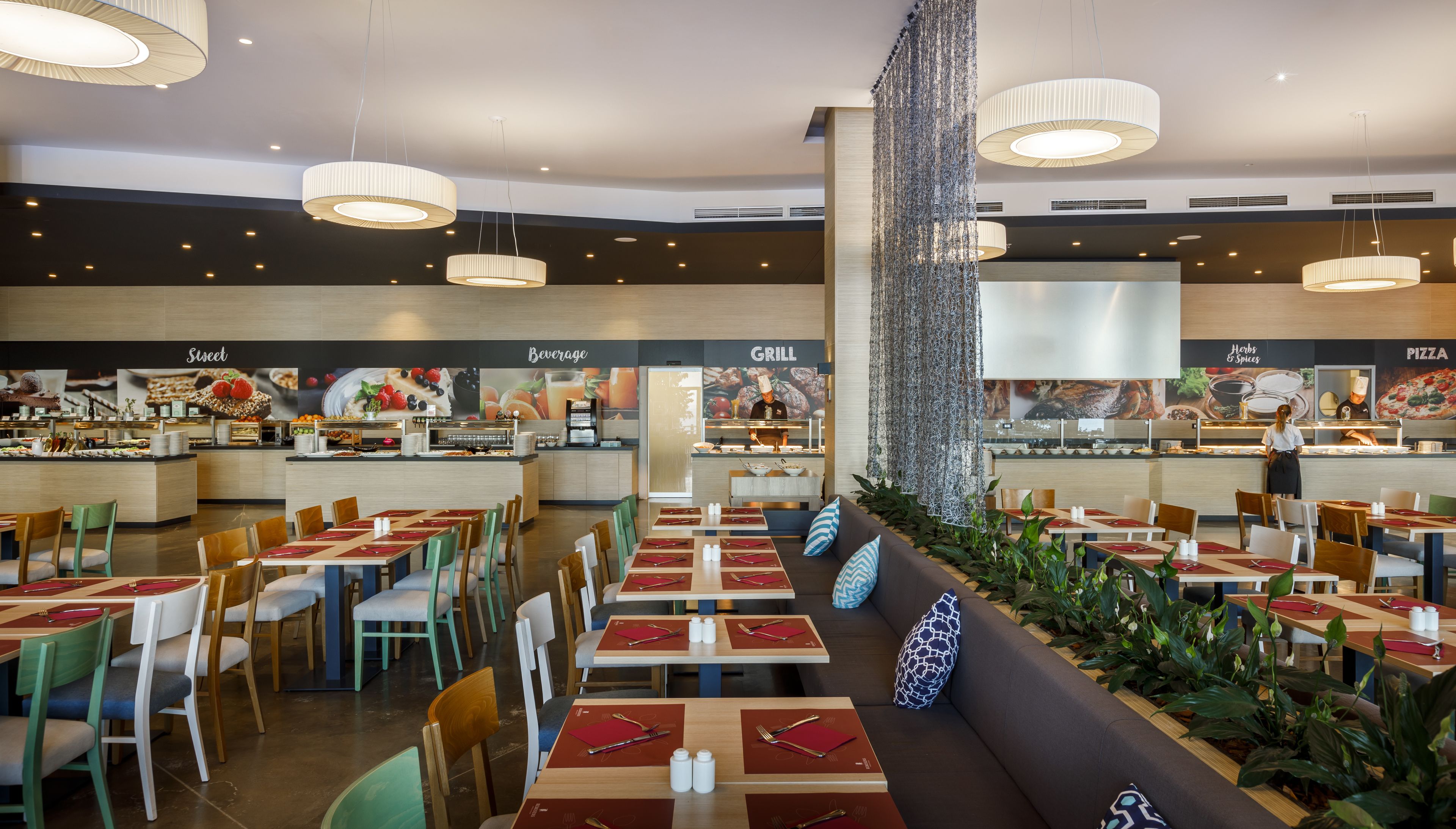 Un restaurante moderno con varias zonas de comedor, una sección de parrilla y un bar de bebidas.