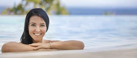 A person relaxing in a pool with a tropical island in the background.