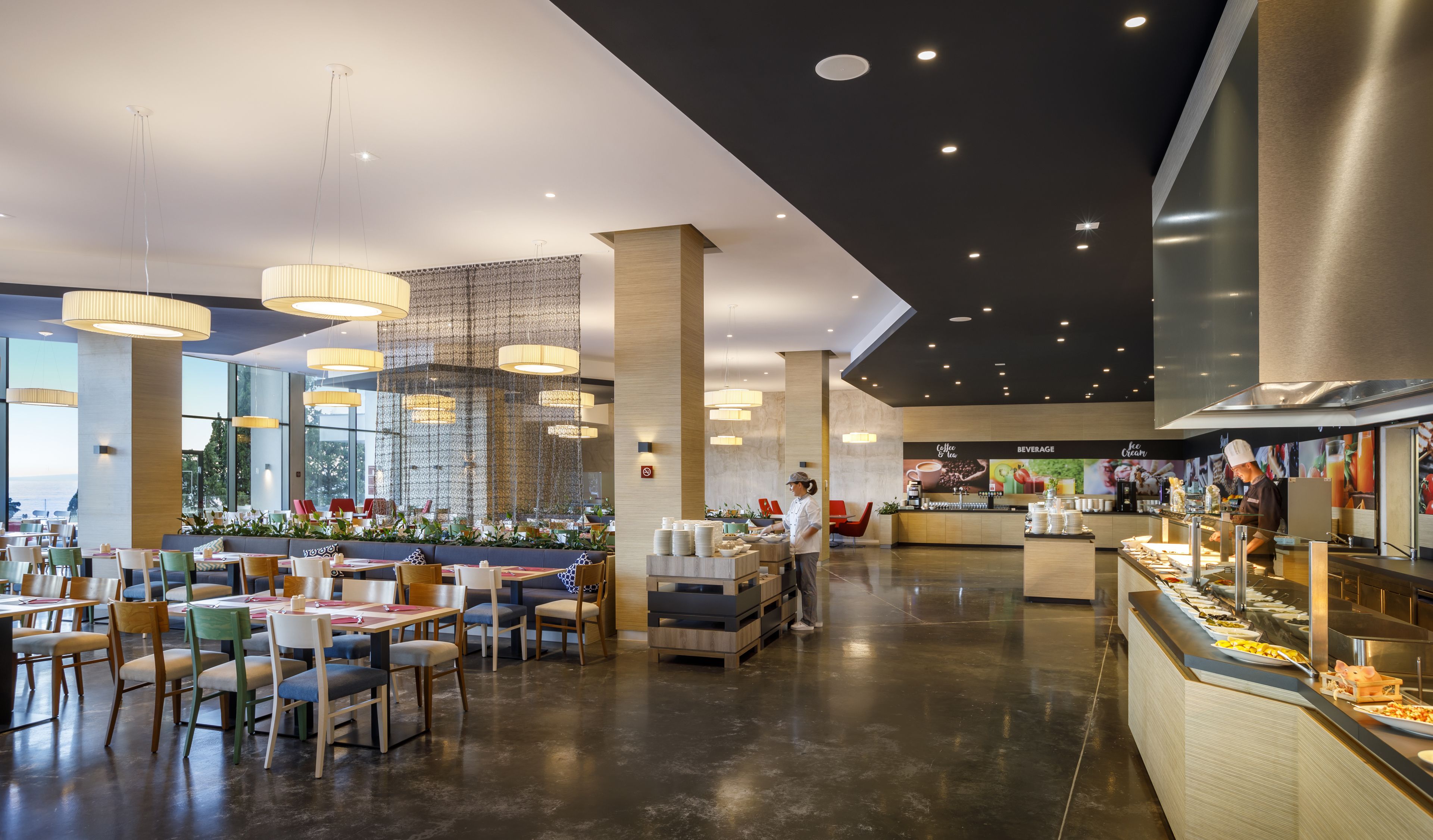Zona de menjador moderna amb sostres alts, il·luminació penjant i un mostrador de buffet.