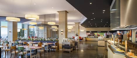 Zona de menjador moderna amb sostres alts, il·luminació penjant i un mostrador de buffet.