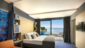 Habitación de hotel moderna con una cama grande, un escritorio y vista al mar.