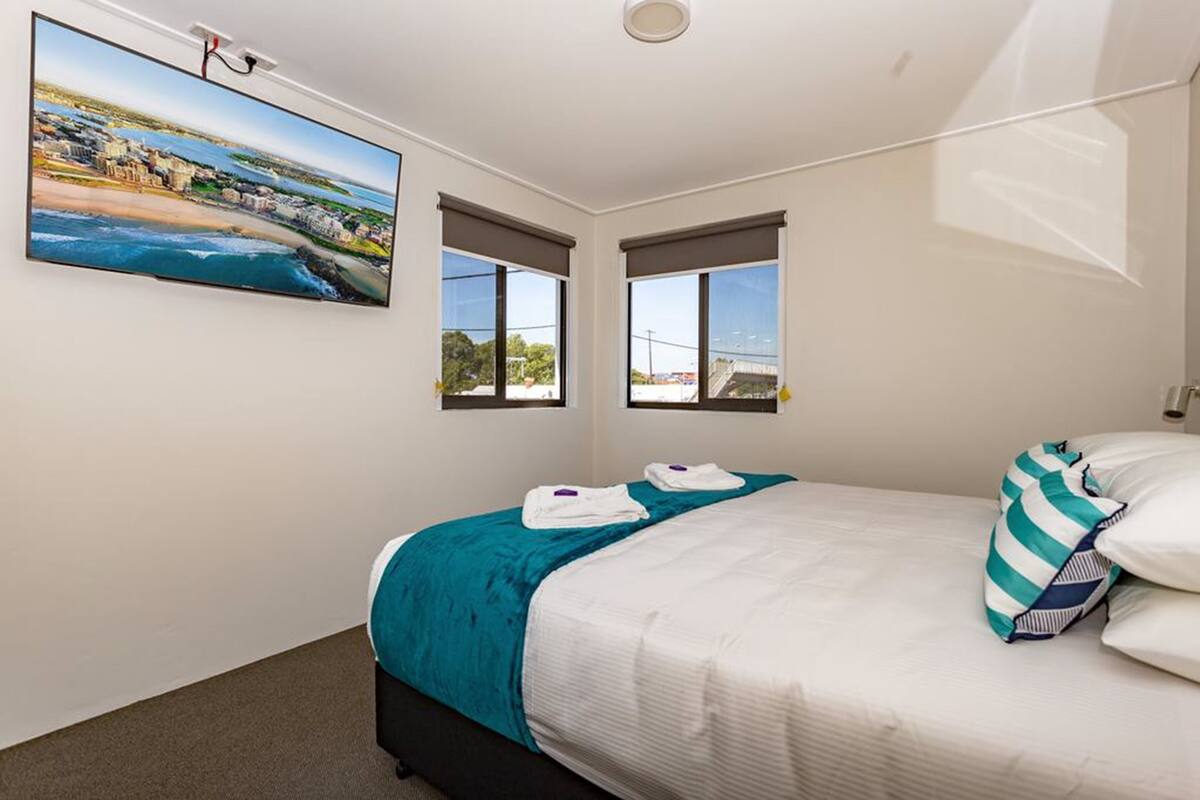 Une chambre d’hôtel avec un lit, une grande fenêtre, un tableau et une vue sur la plage.