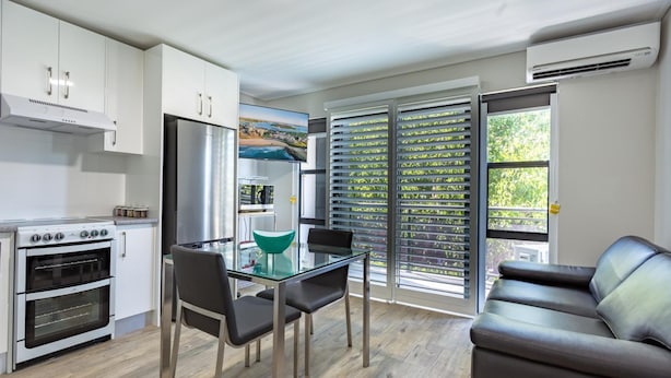 A modern kitchen with white cabinets, a stainless steel refrigerator, and a glass dining table with chairs. - Hamilton on Beaumont (Islington)