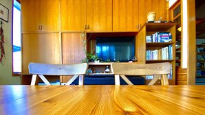 Una mesa de madera para comer con dos bancos en un cuarto con armarios de madera y una estantería.