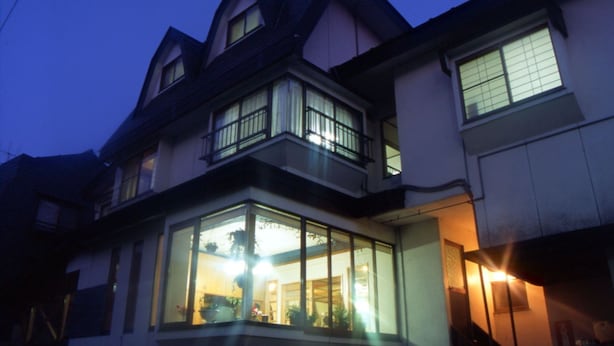 Una casa de varios pisos con ventanas grandes y un balcón.