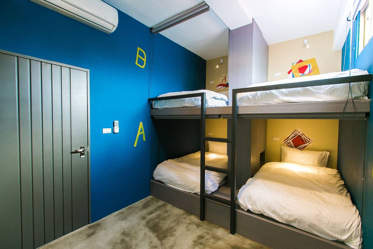 Quarto com beliche, porta, interruptor de luz e ar condicionado fixado na parede.