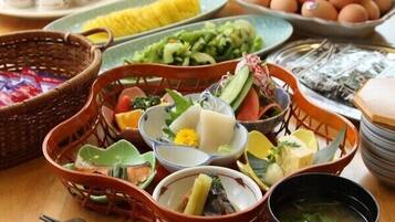 Una mesa con diversos platos, entre ellos un tazón de sopa, un plato de huevos y una cesta de verduras.