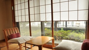 A traditional Japanese room with tatami flooring, a low wooden table, and two tatami mats with cushions. - Ryokan Kichiman (Kochi)