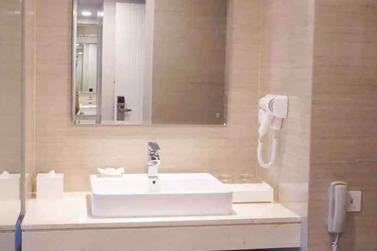 Un baño con un lavamanos blanco, un espejo y un teléfono.