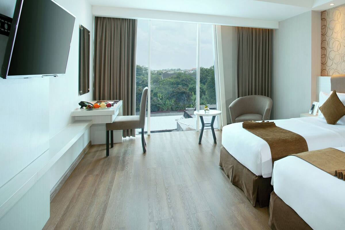 Ein Hotelzimmer mit zwei Betten, einem Schreibtisch, einem Stuhl und einem Fernseher.