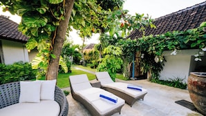 Un patio con sillones de mimbre y una jardinera grande.