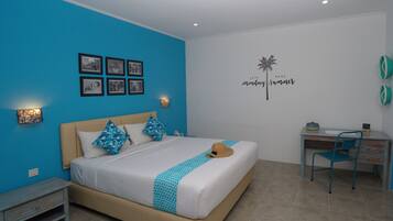 Un dormitorio con cama, escritorio y silla. Hay cuadros en la pared, un adhesivo decorativo y una mesita de noche con una lámpara.