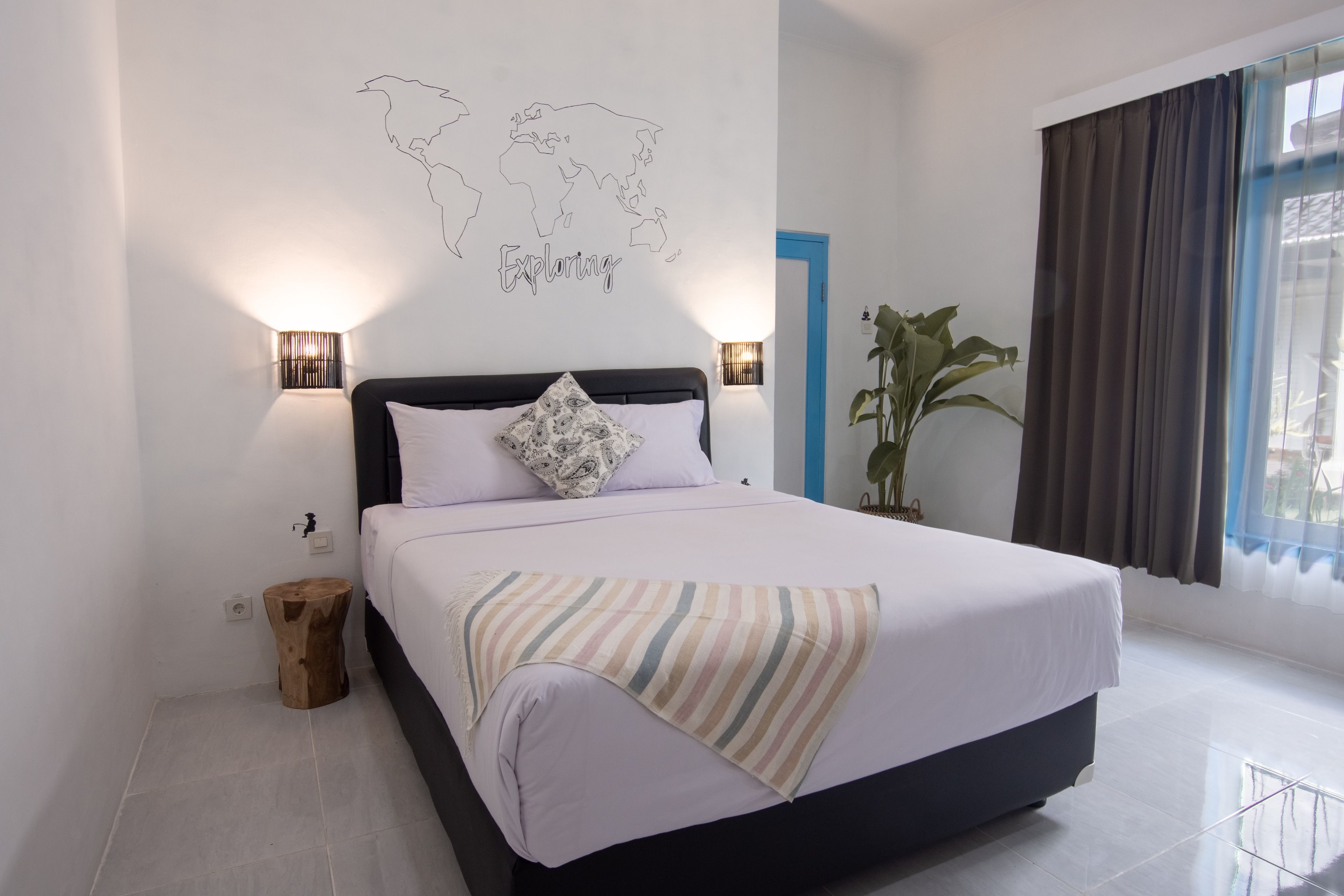 Une chambre à coucher bien rangée, avec un lit, une carte du monde accrochée au mur et une fenêtre avec des rideaux.