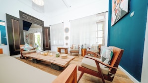 Un salón espacioso con una amplia mesa de centro de madera, varias sillas, un sofá y un espejo grande.