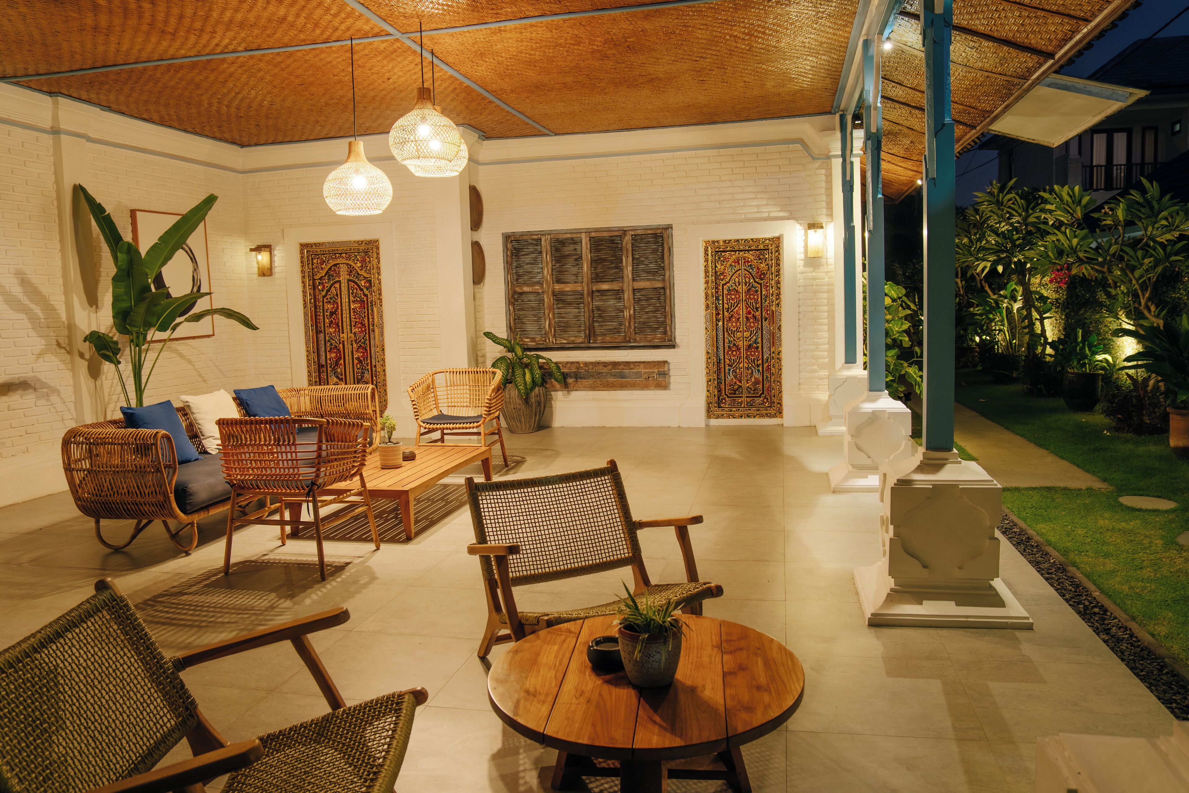 A spacious indoor area with wicker furniture, a round wooden table, and a potted plant.