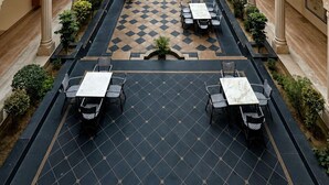 Un patio con un espacio central abierto rodeado de múltiples balcones, con un diseño de piso a cuadros y mobiliario para exteriores.