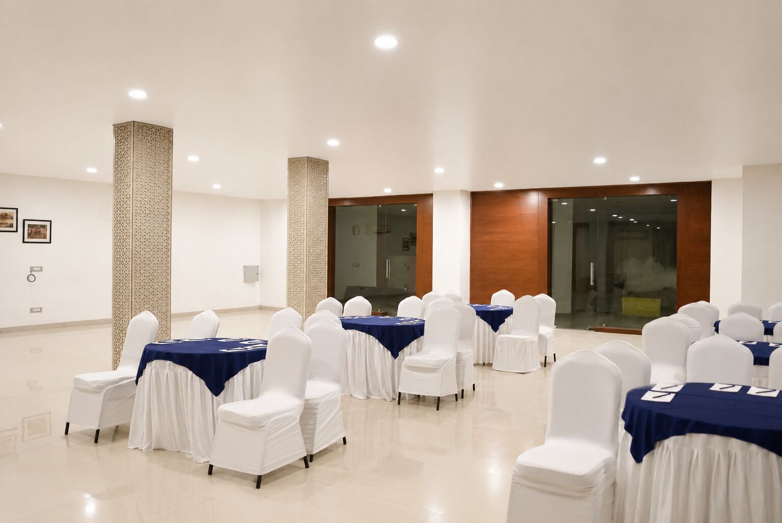 Un salón de conferencias con mesas y sillas, un pilar con diseño y una puerta de cristal.
