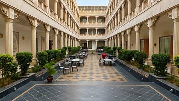A hotel courtyard with a central open space, columns, and potted plants.