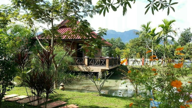 A house with a red roof, surrounded by lush greenery and a small pond. - Maesai Doi View Resort (Mae Sai)