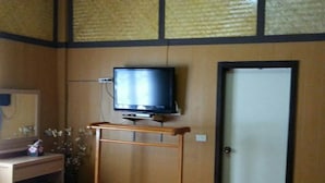 A hotel room with a bed, a desk with a computer, a television on a stand, and a door. - Maesai Doi View Resort (Mae Sai)