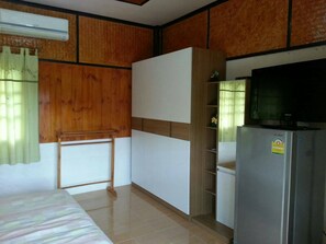 Ein Zimmer mit einem Bett, einem Kleiderschrank, einem Fernseher und einem Kühlschrank.