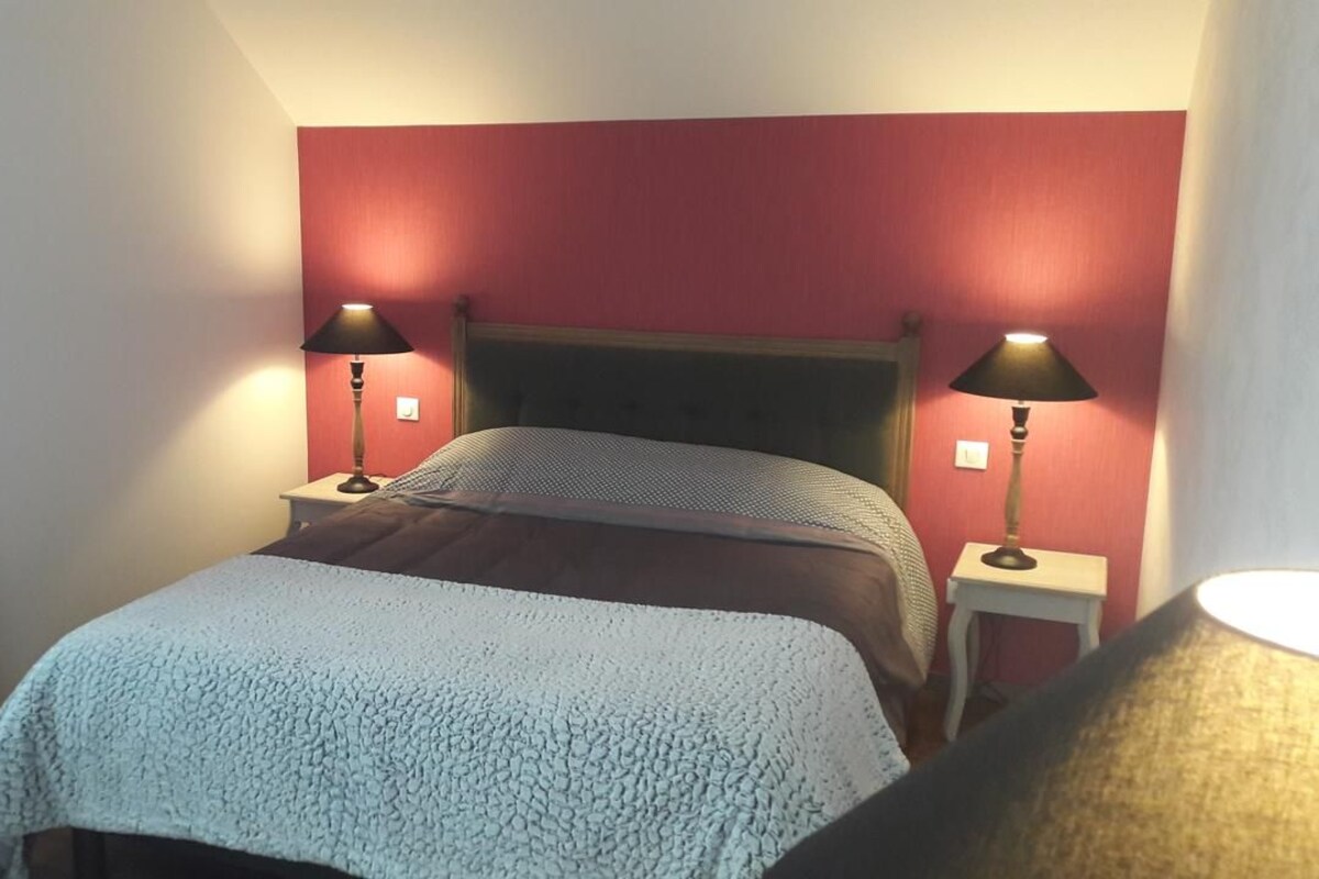Un dormitorio con una cama, dos lámparas de noche y una cortina estampada.