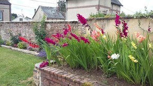 Un jardín con diversas flores y un muro de ladrillo.