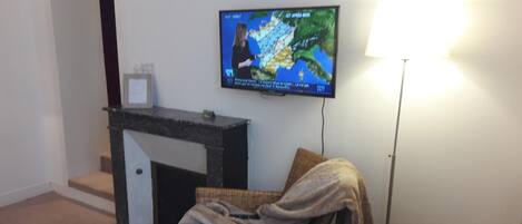 A living room with a television mounted on the wall displaying a weather forecast.