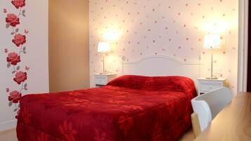 A bedroom with a red bedspread, two bedside lamps, a white nightstand, and a wall with butterfly decals.