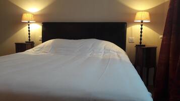 Una cama bien hecha con sábanas blancas en una habitación de hotel. Hay dos mesitas de noche con lámparas a cada lado de la cama.