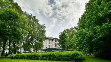 A large building surrounded by lush green trees and a well-maintained lawn.