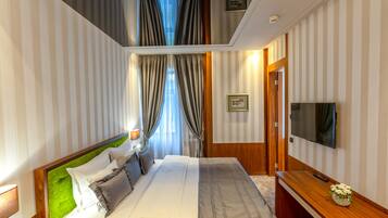 A hotel room with a bed, a TV, a desk, and curtains.