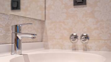 Un baño moderno con un grifo cromado, un lavamanos blanco y un papel tapiz con diseño.