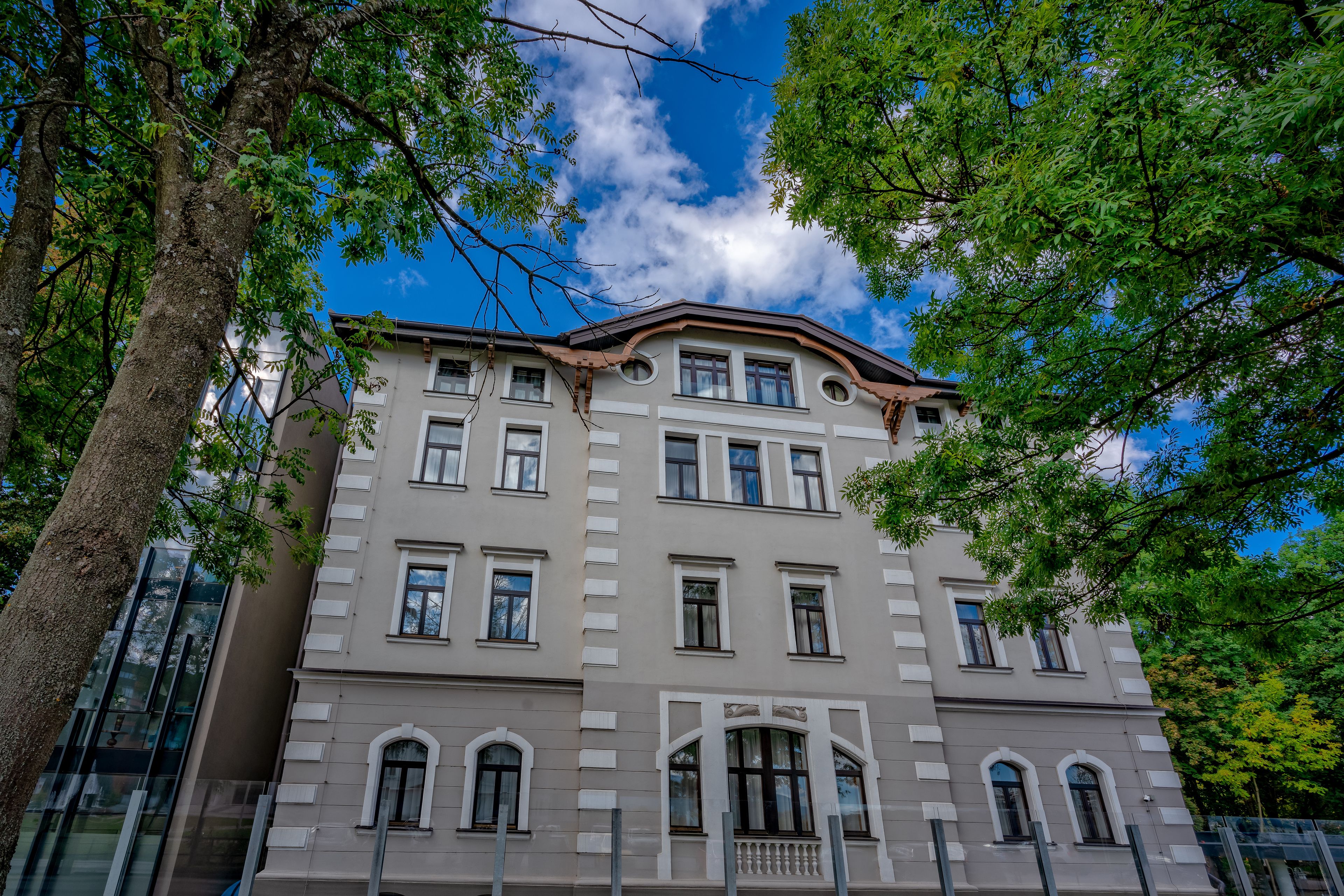 A multi-story building with a classical architectural style, featuring a symmetrical facade, arched windows, and a central entrance with a balcony.