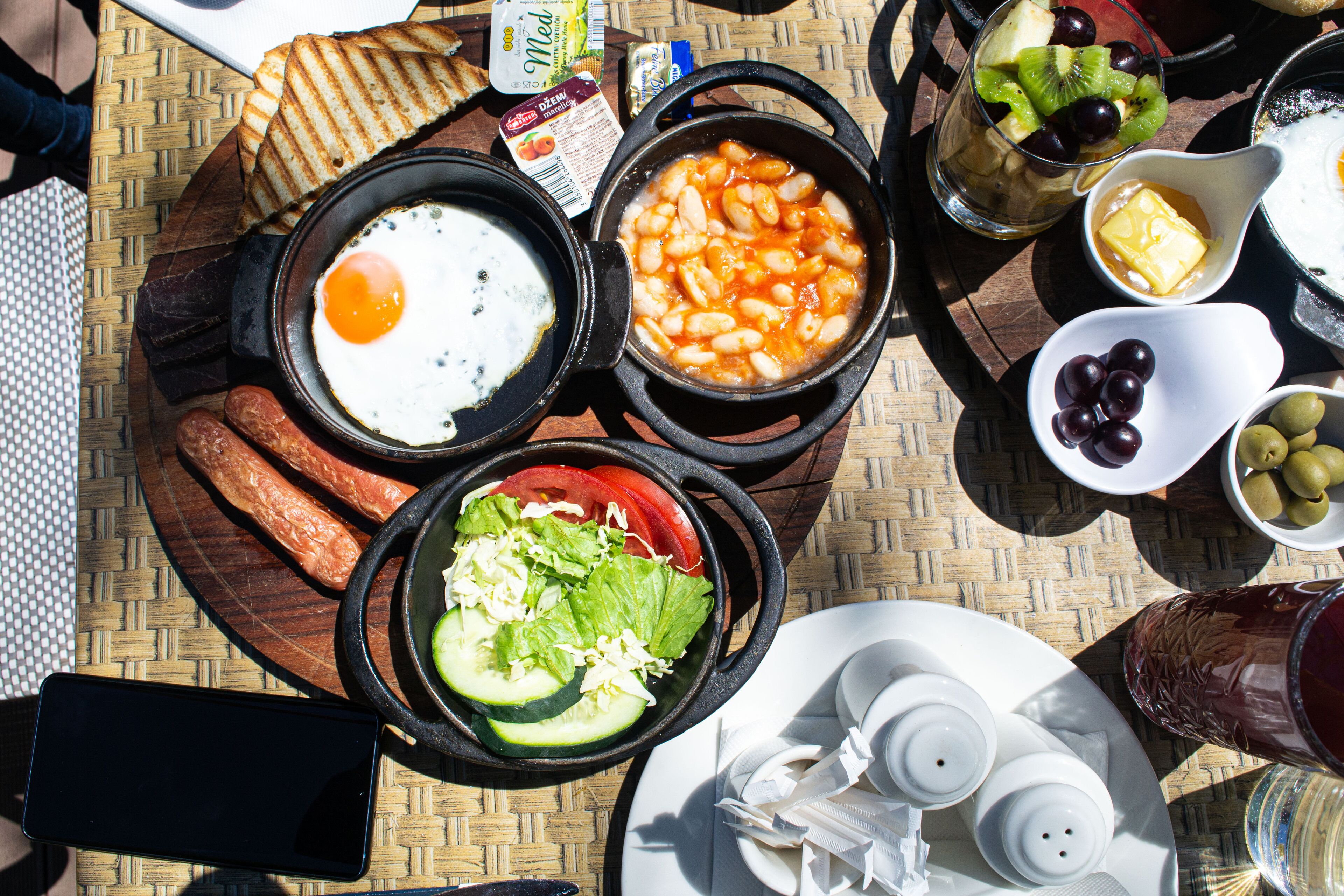 A variety of dishes including eggs, beans, and vegetables, arranged on a woven tablecloth.