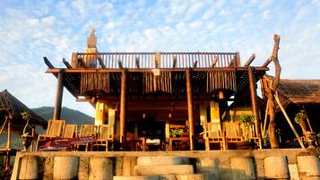A wooden villa with a balcony, outdoor seating, and a view of the mountains.