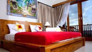A wooden bed with red bedding, a nightstand with a lamp, and a painting of a village scene. - Amed Sunset Beach (Karangasem)