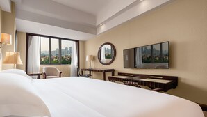 A hotel room with a large bed, a desk, a chair, a TV, and a view of the cityscape through the window. - Country Garden Phoenix Hotel Chongqing (Chongqing)
