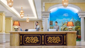 A reception desk with ornate gold detailing, a mural of a grand building, and chandeliers. - Country Garden Phoenix Hotel Chongqing (Chongqing)