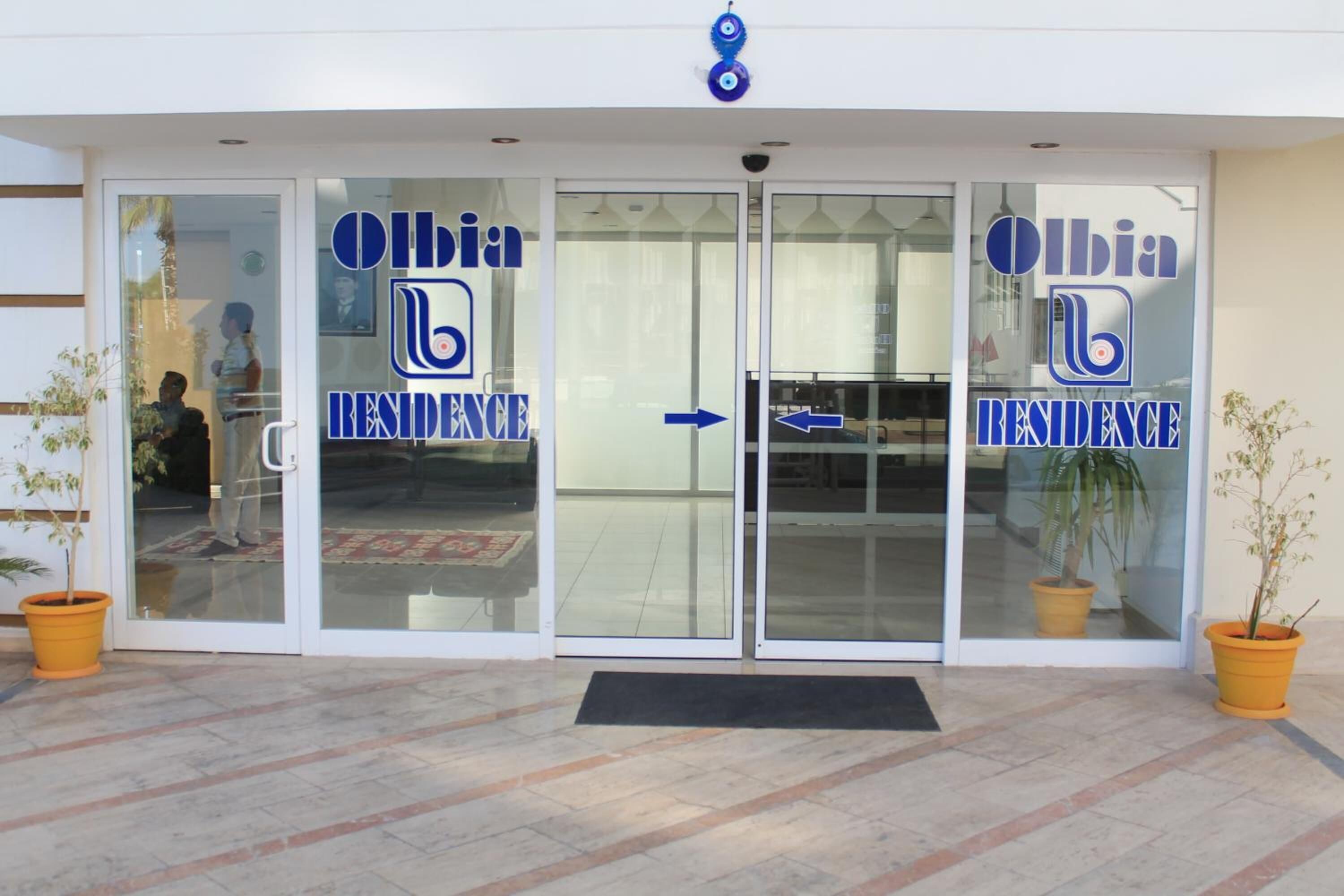 A hotel entrance with glass doors and a sign reading "Olbia Residence".
