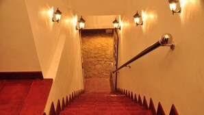 Una escalera con peldaños rojos y una pared de piedra en la parte superior.