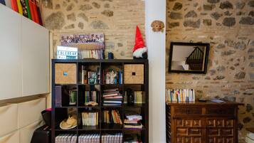 A room with a stone wall, a bookshelf filled with books and decorative items, a wooden cabinet, and a mirror on the wall.